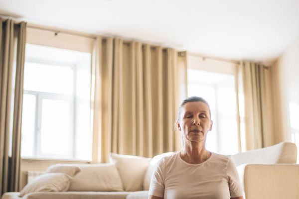 Person calmly meditating in a spacious, light-filled room.